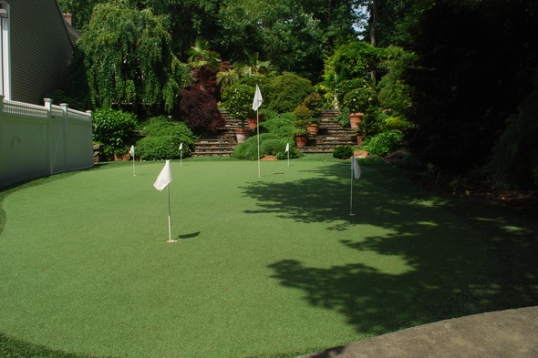 Toronto Synthetic grass golf green with flags in a landscaped backyard