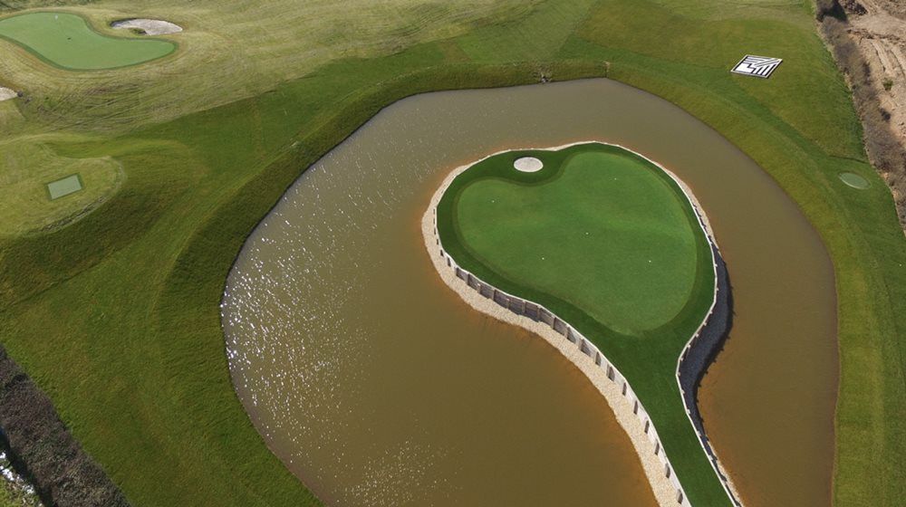 Toronto Aerial view of a vibrant green synthetic grass island in a natural pond on a golf course